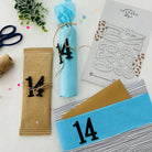 Drei Geschenkpakete mit blauem Seidenpapier, brauner Schnur, Schere und einem Stanzenschablone Große Zahlen Aufkleberbogen von Stanzenshop.de sind auf einer weißen Fläche angeordnet - ideal für Basteln oder Scrapbooking Projekte.