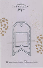 Eine silberne Stanzschablone aus Metall: Anhänger mit quadratischer Klappe gestanzt, abgebildet in Markenverpackung von Stanzenshop.de.