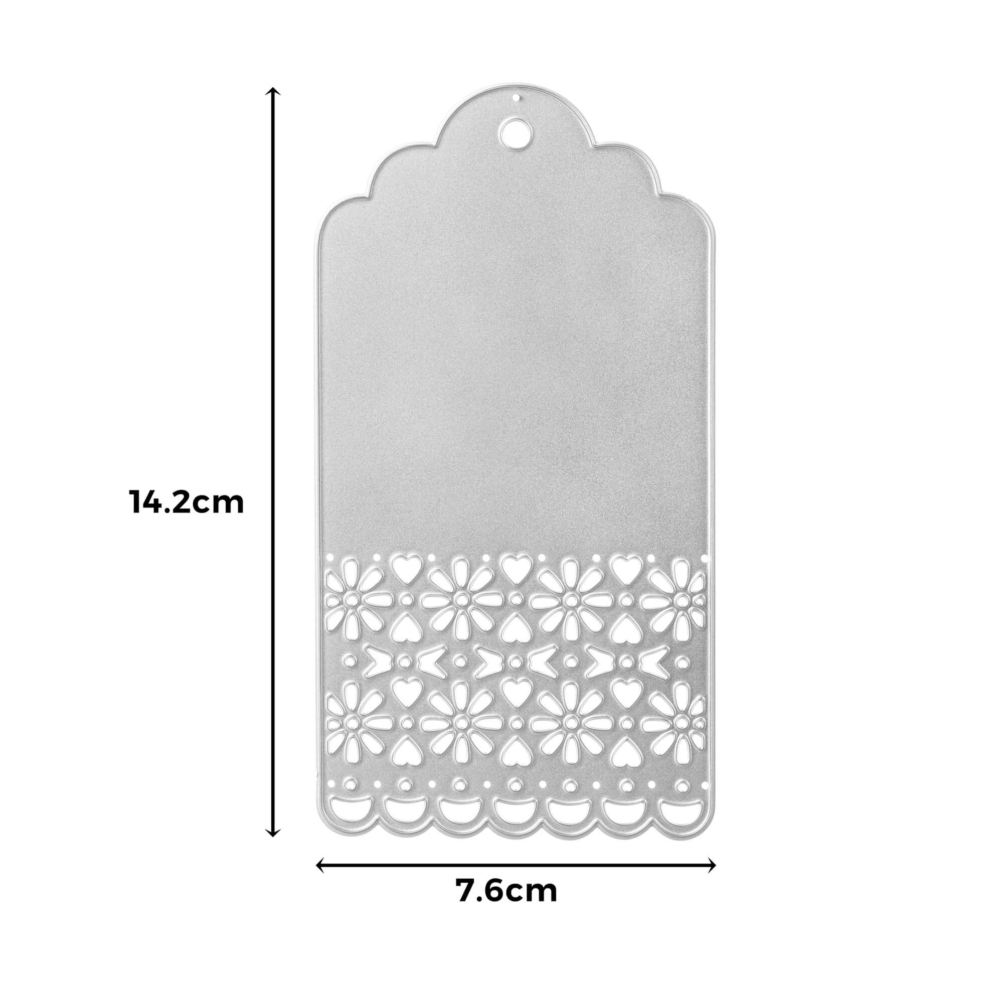 Die Stanzenshop.de Stanzschablone Anhänger mit Verzierung ist eine silberne rechteckige Stanzschablone (14,2 x 7,6 cm) mit einem Blumenausschnitt unten und einem Loch oben - ideal für Scrapbooking oder kreative DIY-Projekte.