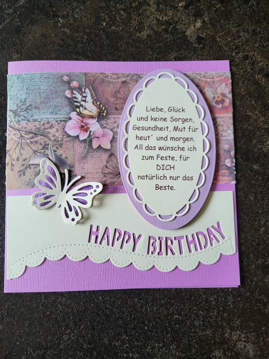 Eine handgefertigte lila und rosa Geburtstagskarte basteln mit einem Schmetterling, floralem Hintergrund, deutscher Geburtstagsnachricht in einem ovalen Rahmen und dem Stanzenshop.de Stanzschablone: Happy Birthday Wimpel Gruß.