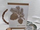 Diese handgefertigte Karte zeigt ausgeschnittene Tannenzweige und Zapfen mit der Stanzschablone: Zapfenzweig von Stanzenshop.de, verziert mit einer goldenen Schleife und dem Schriftzug "Liebe Grüße zum Weihnachtsfest" - ideal zum Basteln oder Scrapbooking.