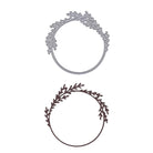 Die Stanzschablone Kranz mit Zweigen von Stanzenshop.de umfasst zwei runde Rahmen mit blattartigen Zweigmotiven oben links - einer in Silber, einer in tiefem Dunkelbraun - ideal als filigraner Kranz für Bastelprojekte.