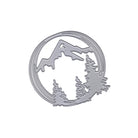 Die Stanzschablone Bergpanorama im Kreis von Stanzenshop.de ist ein silberner Metallstempel in Kreisform mit Berg- und Tannenbaummotiv - ideal für Bastelprojekte.