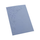 Eine hellblaue Karte mit dem Embossing Folder "Schneeflockenrahmen mit Sternen" von Stanzenshop.de geprägt, zeigt Schneeflocken und Ornamente in einer Ecke auf weißem Hintergrund.