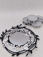 Die Stanzschablone Zwei Kreise mit Blumen von Stanzenshop.de ruht neben drei weißen Teelichtkerzen mit schwarzem Druckmotiv - ideale Akzente für Scrapbooking oder Kartenherstellung - auf einer strukturierten weißen Oberfläche.