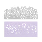 Die Stanzschablone Rand mit Blumen von Stanzenshop.de, eine silberne Metallstanze mit floralem Design, ist über lila Papier mit dem passenden Muster abgebildet - ideal für Scrapbooking oder Kartengestaltung.