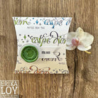 Eine Kissenschachtel aus der "Stanzschablone Fünf lange Wimpel" von Stanzenshop.de mit dem Text "CARPE DIEM" und einem grünen Wachssiegel ruht auf Holz neben einer weißen Orchidee - ideal für Scrapbooking oder zum Verschenken.