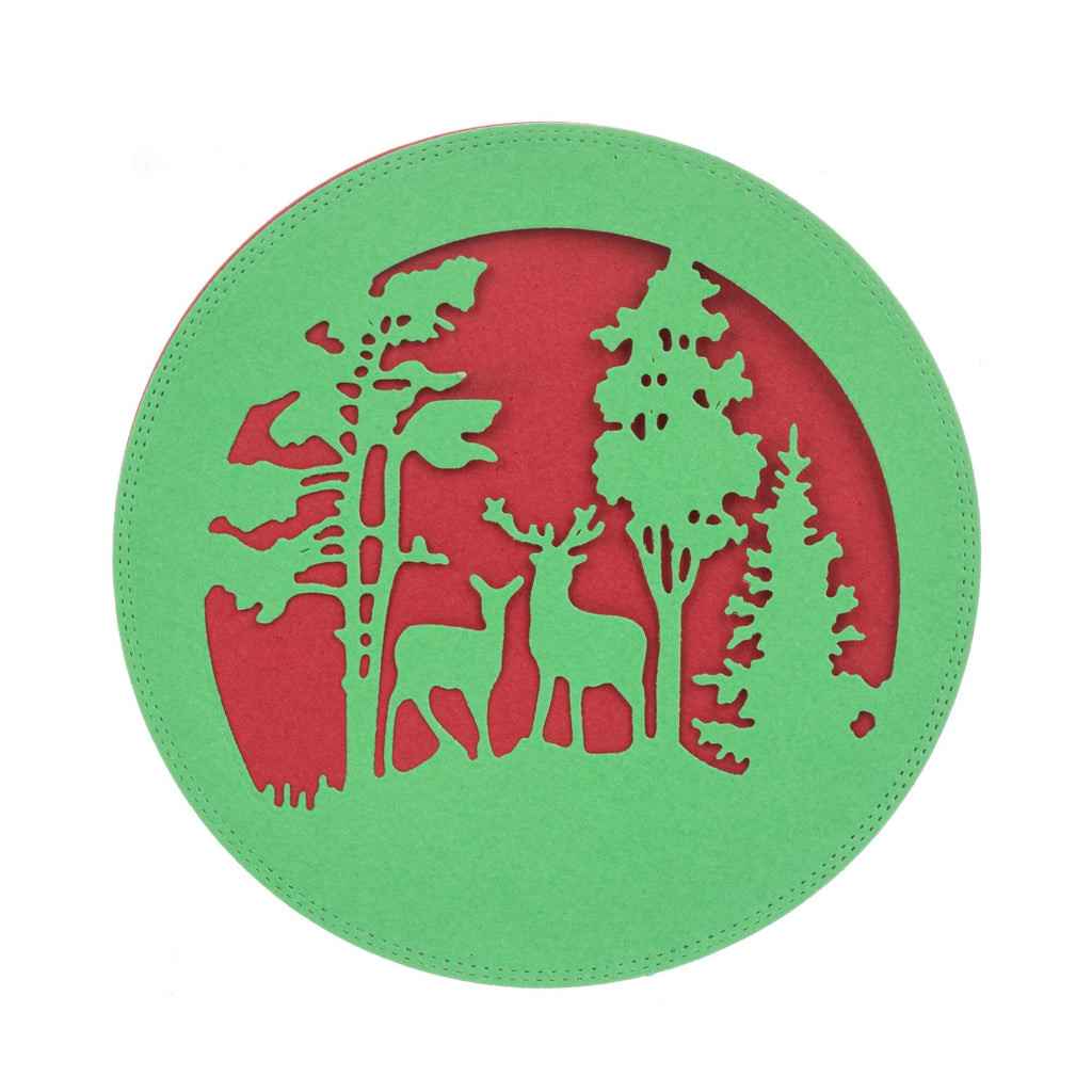 Kreisförmige, grüne ausgeschnittene Silhouette von zwei Hirschen, die zwischen Bäumen vor einem roten Hintergrund stehen, perfekt für Weihnachtsbasteleien mit der Stanzschablone: Winterlandschaft im Halbkreis von Stanzenshop.de.