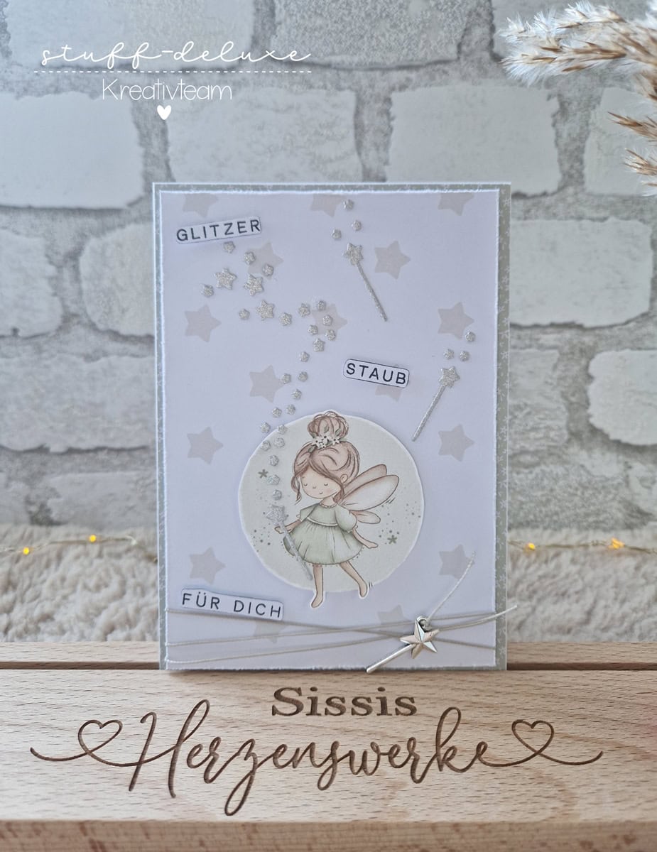 Eine handgefertigte Karte, die die Stanzschablone von Stanzenshop.de zeigt: Reihe aus Sternen und dem deutschen Text "Glitzer Staub für dich" - ein entzückendes Scrapbooking-Ergebnis - auf einem Holzständer mit der Aufschrift "Sissis Herzenswerke" präsentiert.