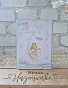 Eine handgefertigte Karte, die die Stanzschablone von Stanzenshop.de zeigt: Reihe aus Sternen und dem deutschen Text "Glitzer Staub für dich" - ein entzückendes Scrapbooking-Ergebnis - auf einem Holzständer mit der Aufschrift "Sissis Herzenswerke" präsentiert.