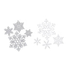 Stanzschablone Vier Schneeflocken in verschiedenen Größen von Stanzenshop.de: detailreiche Silber- und Weiß-Schneeflocken, ideal zum Scrapbooking oder Basteln, auf weißem Hintergrund arrangiert.
