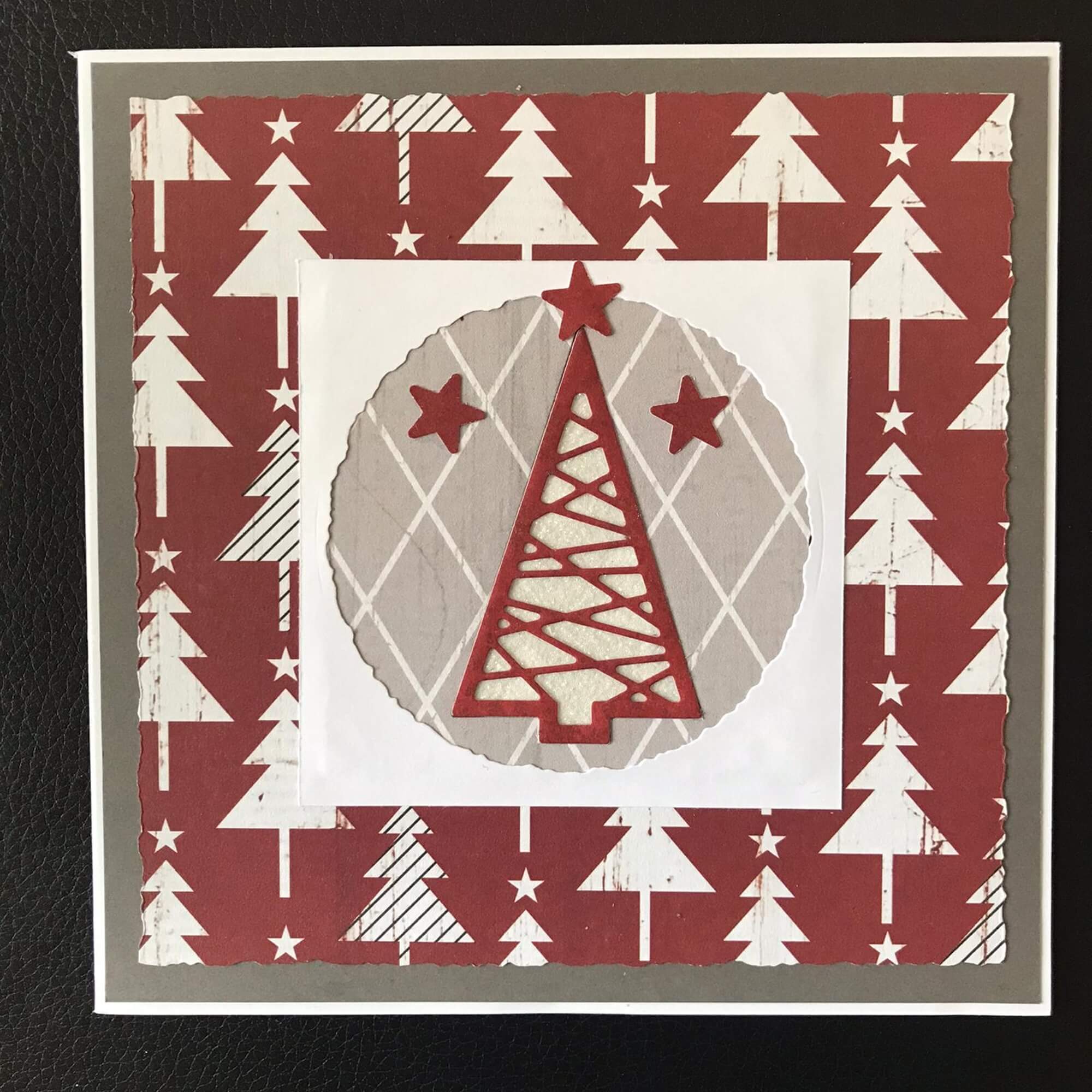 Basteln Sie mit der "Stanzschablone Drei verschiedene Tannenbäume" von Stanzenshop.de - eine handgefertigte Weihnachtskarte mit stilisierten roten und weißen Tannenbäumen und Sternakzenten auf gemustertem Hintergrund. Perfekt für kreatives Basteln!.