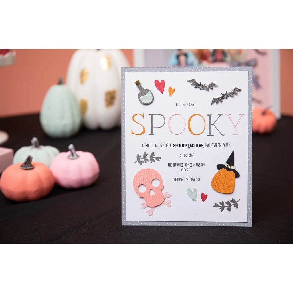 Einladungskarte für eine Halloween-Party mit dem Wort „SPOOKY“ und Veranstaltungsdetails. Um die Karte herum sind kleine dekorative Kürbisse, Halloween-Symbole und festliche Ornamente. Verschönern Sie Ihre Designs mit dem Sizzix • Thinlits Die Set Spooky Icons oder einem Skull Bigz Die für eine unheimliche Note.