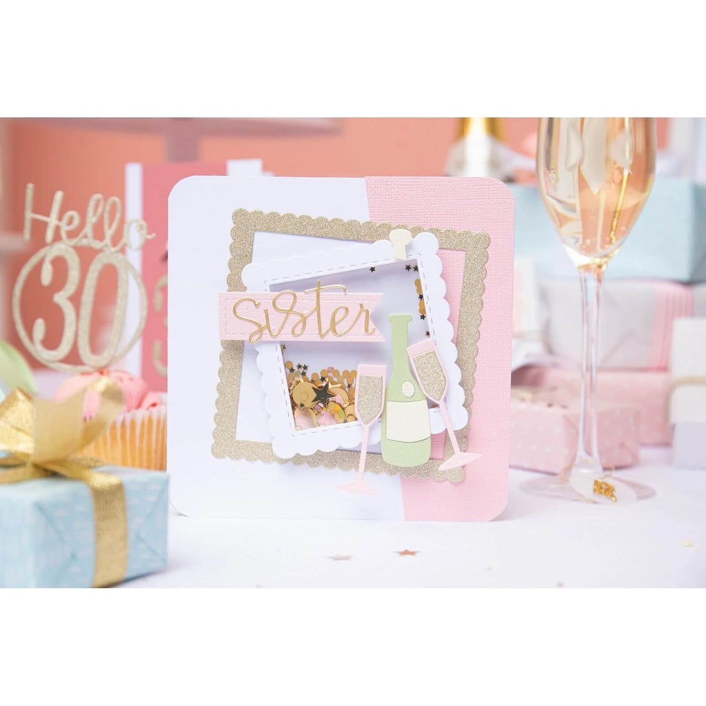 Eine rosa-weiße Sizzix-Geburtstagskarte mit einer Champagnerflasche in den Sizzix Fabulous Frames & Borders von Debi Potter.