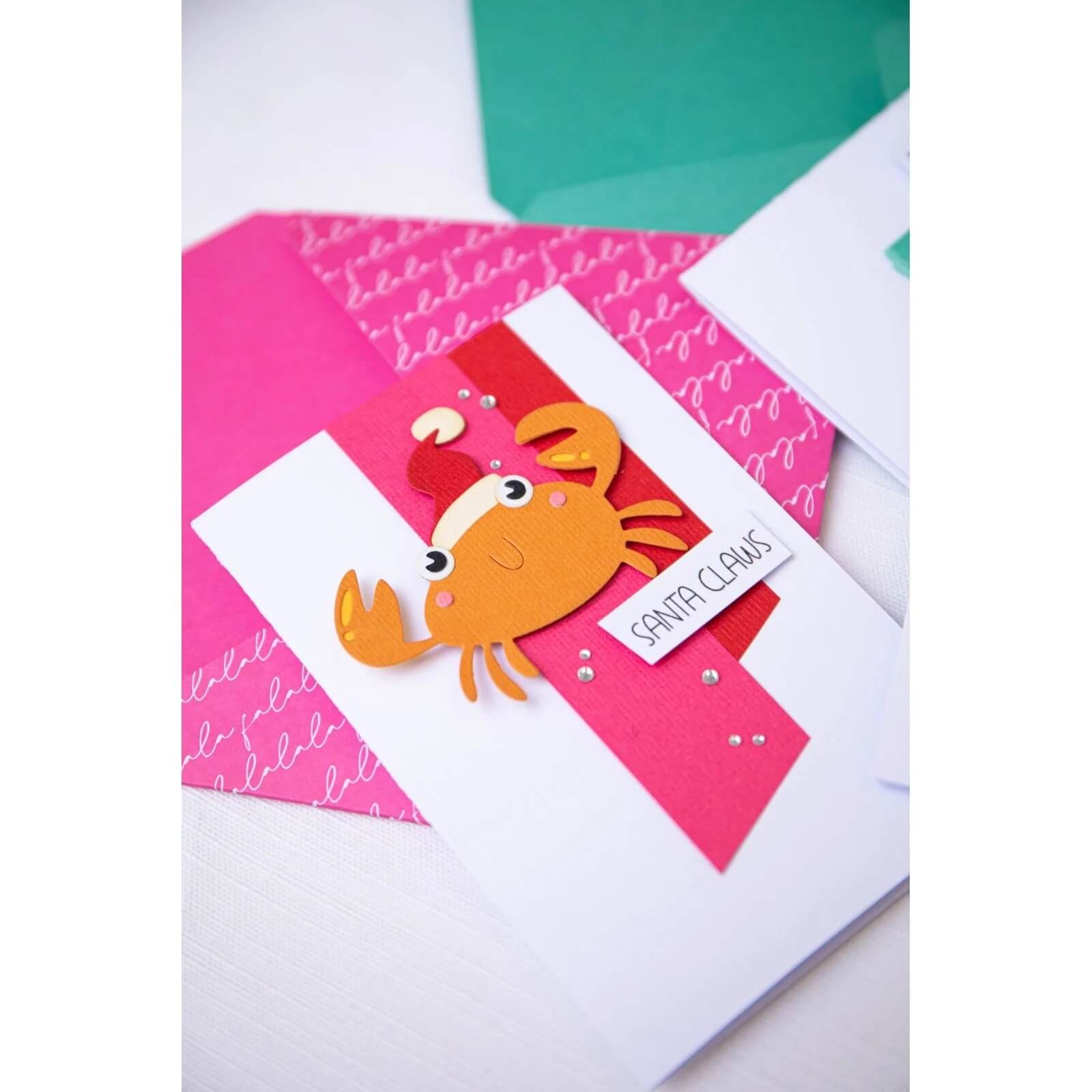 Das Set Sizzix 666313 Thinlits with Stamps Christmas Characters von Sizzix ist perfekt, um verspielte Weihnachtsfiguren wie eine Cartoon-Krabbe mit Weihnachtsmannmütze und "Santa Claws"-Aufkleber zu Ihren Kartenbasteln oder festlichen Basteleien hinzuzufügen.