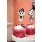 Zwei Cupcakes mit weißem Zuckerguss in rosafarbenen Verpackungen, gekrönt mit Vampir- und Skelett-Papiertoppern sowie einer Plastikspinne - perfekt für Halloween-Papierbastelprojekte mit den Sizzix 666315 - Thinlits mit Stamps Spooky Friends von Sizzix.