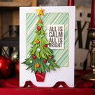 Eine handgefertigte Weihnachtskarte mit einem geschmückten Baum und "Alles ist ruhig, alles ist hell" auf Streifen, hergestellt mit den Sizzix 666332 Thinlits Stanzschablonen Trim a Tree Colorize von Sizzix.