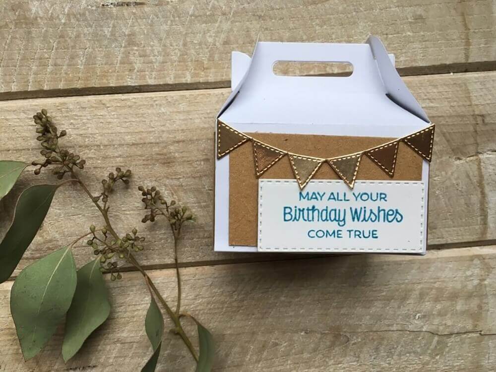 Eine Schachtel mit Eukalyptusblättern und einer Geburtstagskarte verziert mit der Stanzschablone Vier verschiedene Wimpelketten von Stanzenshop.de.