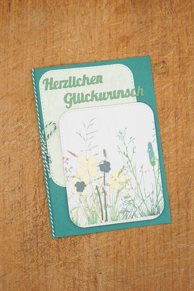 Eine hölzerne Stanzschablone Sechs Rahmen mit runden Ecken mit einer mit zarten Blumen verzierten Karte von Stanzenshop.de.