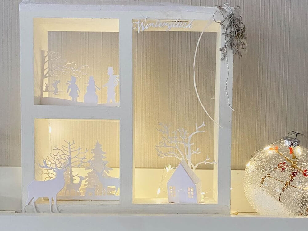 Ein Kleines Haus Stanzschablone Bastelset Kaminsims mit einer Weihnachtsszene aus Papier von Stanzenshop.de.