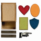 Eine kleine offene Pappschachtel, die mit den Sizzix 666604 Thinlits Vault Streichholzschachtel (10 Stück) von Sizzix hergestellt wurde, sitzt neben sechs farbigen Formen: rotes Herz, orangefarbenes Oval, grünes Rechteck, blaues Schild, zwei schwarze Balken und eine schwarz-weiße Zeigerhand - ideal für kleine Bastelarbeiten.