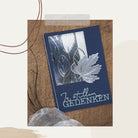 Die Stanzschablone: Ahornblatt von Stanzenshop.de zeigt eine dunkelblaue Grußkarte mit silbernen Blattmotiven und "In stillem Gedenken" auf Deutsch, ideal für Scrapbooking oder Basteln, auf einem braunen strukturierten Hintergrund.