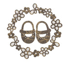 Die Stanzschablone "Babyschuhe im Blütenkranz" von Stanzenshop.de zeigt niedliche Babyschuhe, die von einem zarten Blütenkranz umrahmt werden und eine harmonische, florale Bordüre bilden.
