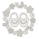 Die Stanzschablone Babyschuhe im Blütenkranz von Stanzenshop.de zeigt Babyschuhe, umgeben von Blumen und Schleifen-ideal für kreative Bastelprojekte.