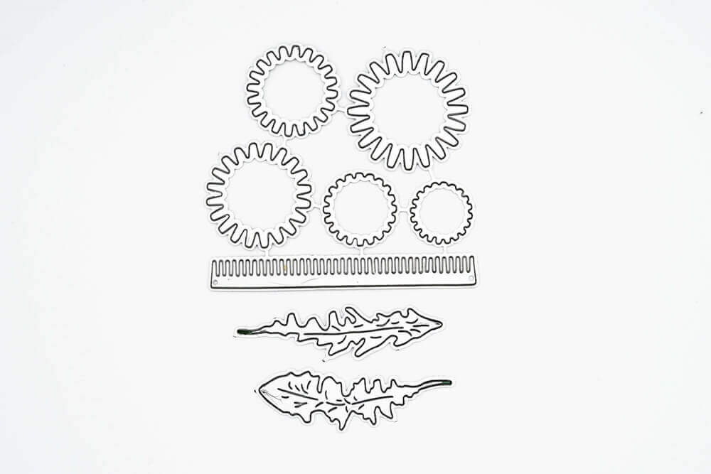 Die sechs Metallstanzformen aus der Stanzschablone Bastelset Löwenzahn von Stanzenshop.de umfassen vier einzigartige Zahnradformen, einen geschlitzten Streifen und zwei Blattkonturen - ideal für Scrapbooking oder kreative Projekte.