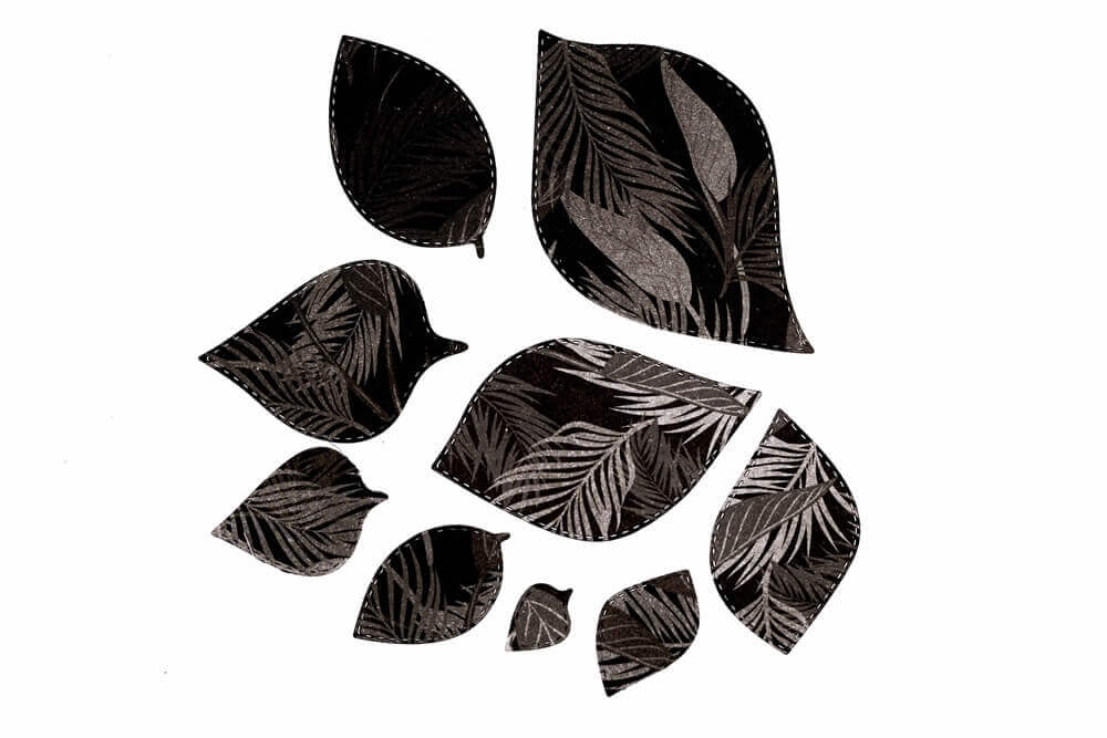 Neun schwarze blattförmige Ausschnitte mit weißen botanischen Mustern werden auf weißem Hintergrund dargestellt - ideal zum Basteln mit der "Stanzschablone: Blätter in verschiedenen Größen" von Stanzenshop.de.