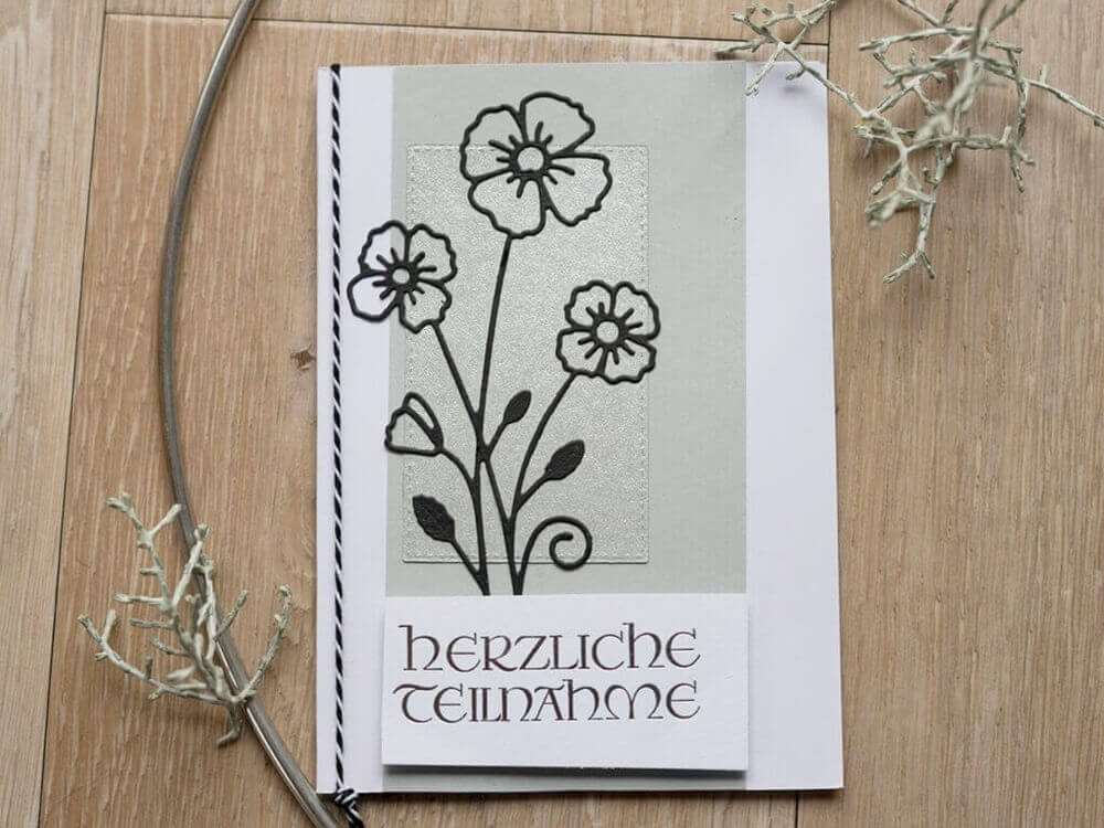 Handgefertigte Kondolenzkarte mit Stanzschablone „Blume mit drei Blüten“ und der Botschaft „Herzliche Teilnahme“ von Stanzenshop.de.