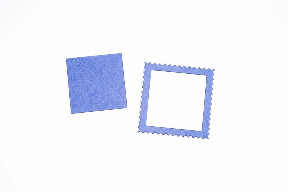 Eine Stanzschablone: Briefmarke von Stanzenshop.de, ein blauer Rahmen und ein Stück Papier auf einer weißen Fläche.