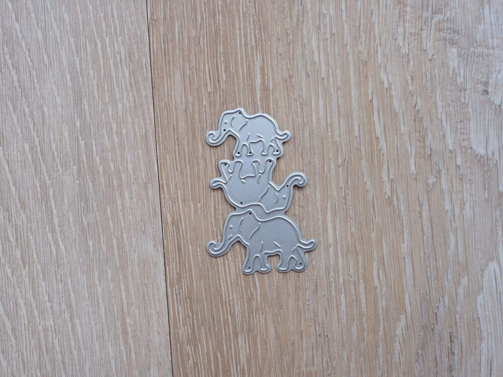 Drei silberne Elefantenausschnitte aus der Stanzschablone Drei Elefanten von Stanzenshop.de sind auf einer hellen Holzfläche gestapelt - ideal für Scrapbooking- oder Bastelprojekte.