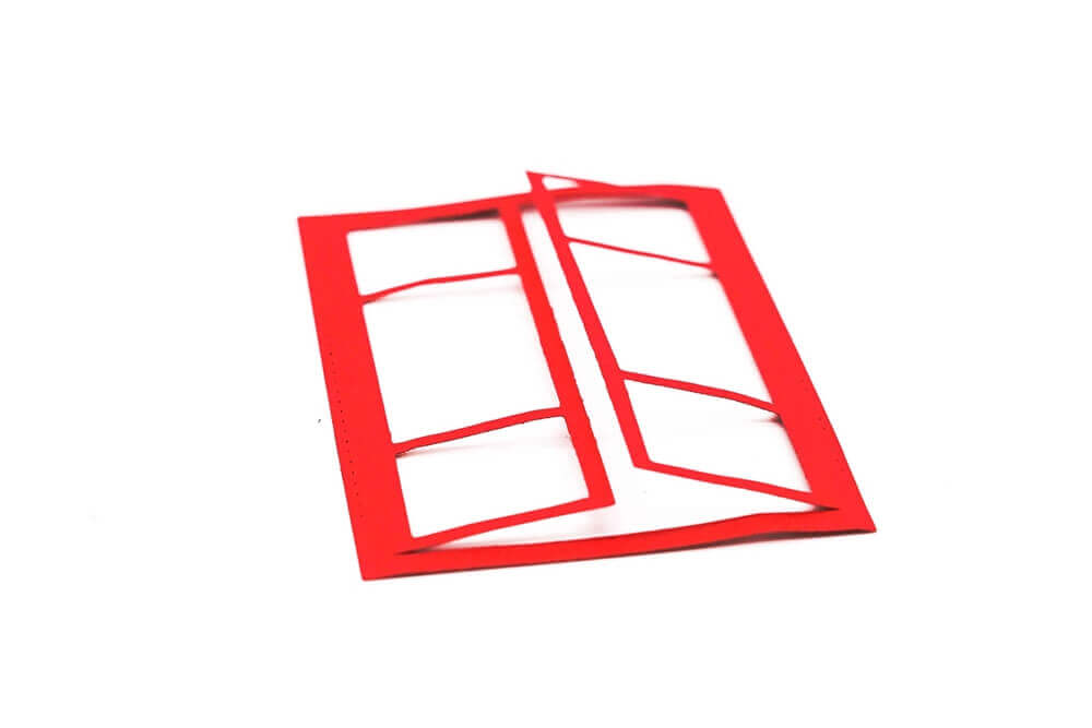 Eine rote Stanzschablone: Fenster-Telefonzelle auf einer weißen Fläche.