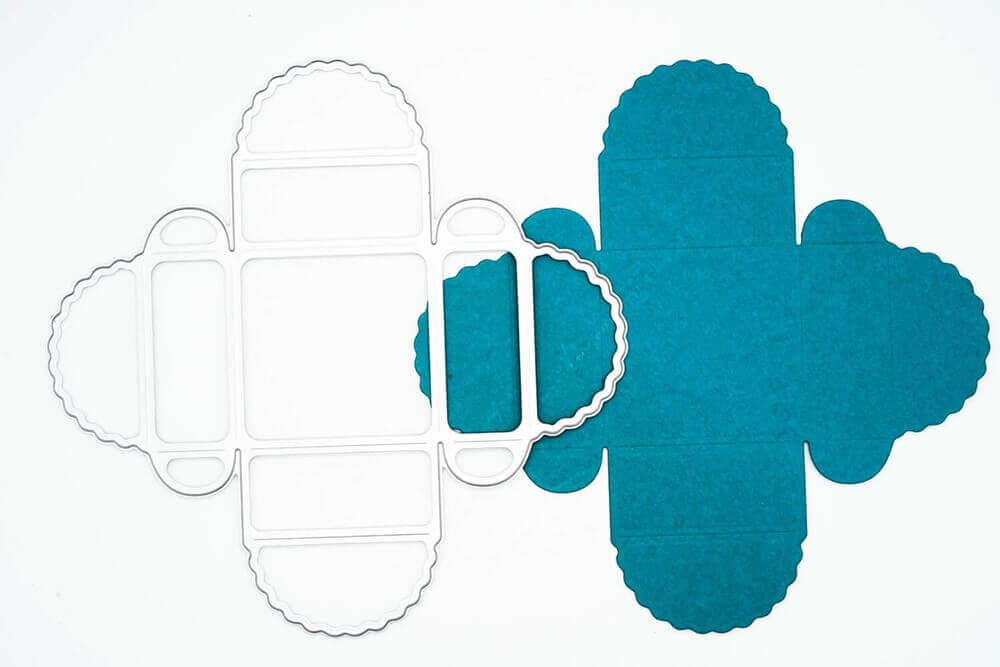 Die Stanzschablone Geschenkkästchen von Stanzenshop.de und der dazugehörige Papierausschnitt mit Wellenschliff sind nebeneinander abgebildet - ideal zum Basteln oder kreativen Scrapbooking auf weißem Hintergrund.