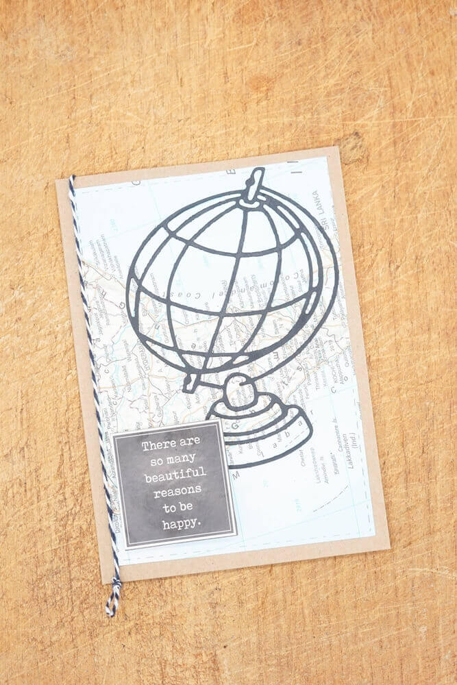 Handgefertigte Stanzschablone: Großer Globus-Grußkarte mit inspirierendem Zitat auf Holzhintergrund von Stanzenshop.de.