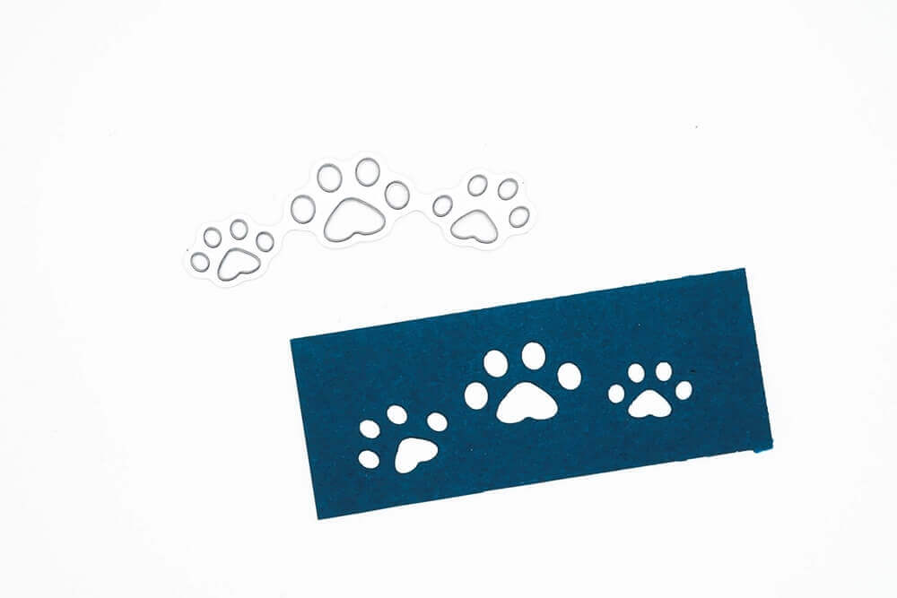 Eine blaue Karte mit Pfotenabdrücken, hergestellt aus hochwertigem Papier mit Stanzmaschinen und Stanzschablone Hundepfoten von Stanzenshop.de.