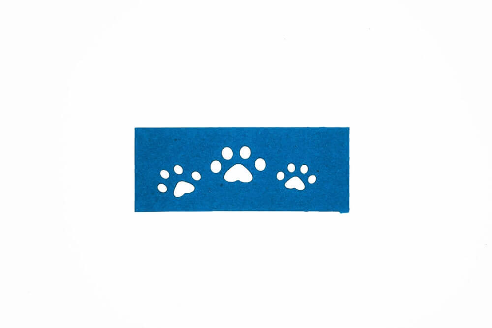 Ein blauer Hintergrund mit Pfotenabdrücken auf Stanzschablone Hundepfoten von Stanzenshop.de auf hochwertigem Papier.