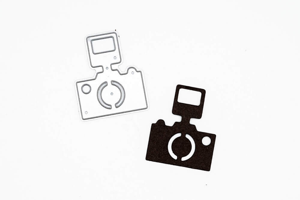 Ein Paar Stanzschablonen: Kamera mit Blitz Aufkleber von Stanzenshop.de auf einer weißen Fläche.