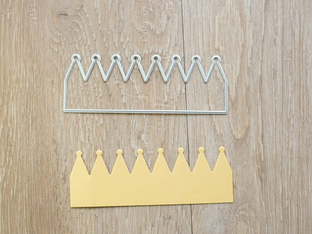 Kronenpapierkronen mit Stanzschablonen auf einem Holzboden.