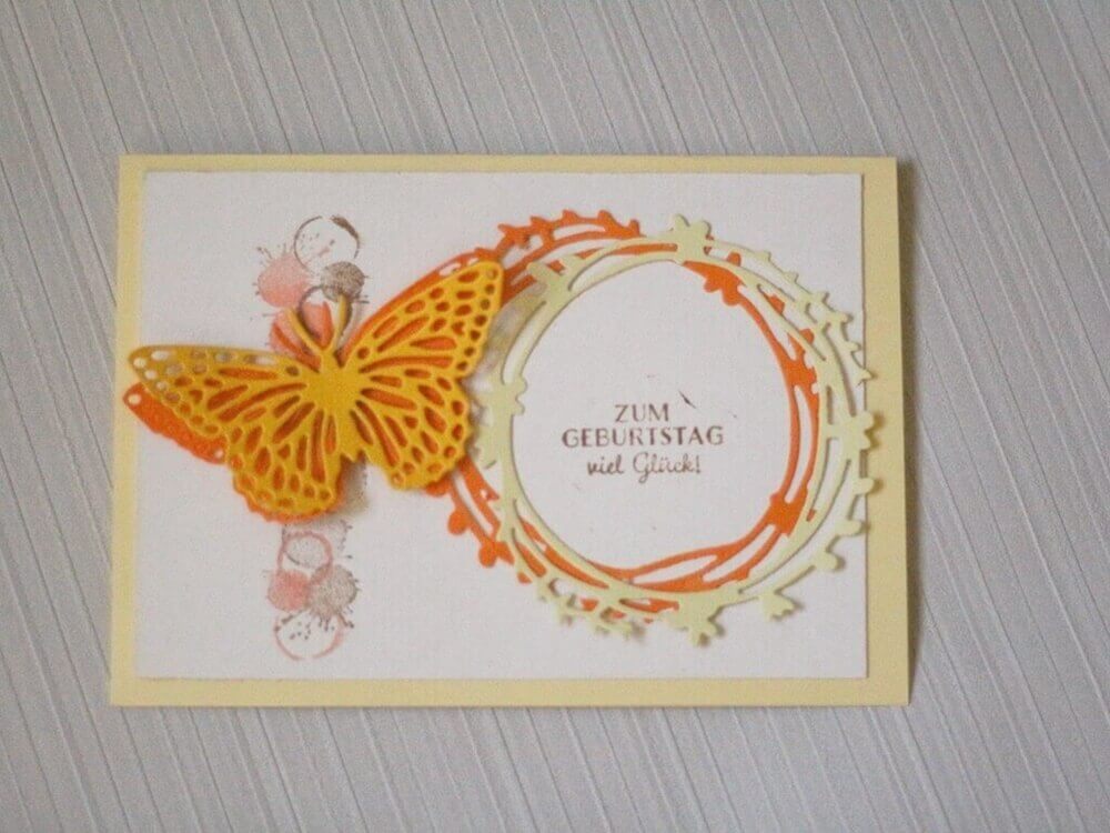Handgefertigte Geburtstagskarte mit Stanzschablone Schmetterling mit extra Umriss von Stanzenshop.de, mit rundem Rahmen und "Zum Geburtstag viel Glück!" - ideal für Bastel-Fans auf hellem Hintergrund.
