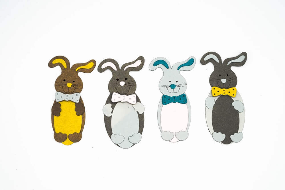 Vier Papierausschnitte von Cartoon-Hasen mit Fliege, die in einer Reihe angeordnet sind - perfekt für Osterbasteleien mit der "Stanzschablone: Süßer Osterhase" von Stanzenshop.de.