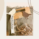 Eine verpackte Vogelfutterkugel mit einem "Piepshowfutter"-Anhänger, dekoriert mit der Stanzschablone Vier verschiedene Vögel von Stanzenshop.de in Weiß und Braun, ausgestellt auf strukturiertem Stoff.