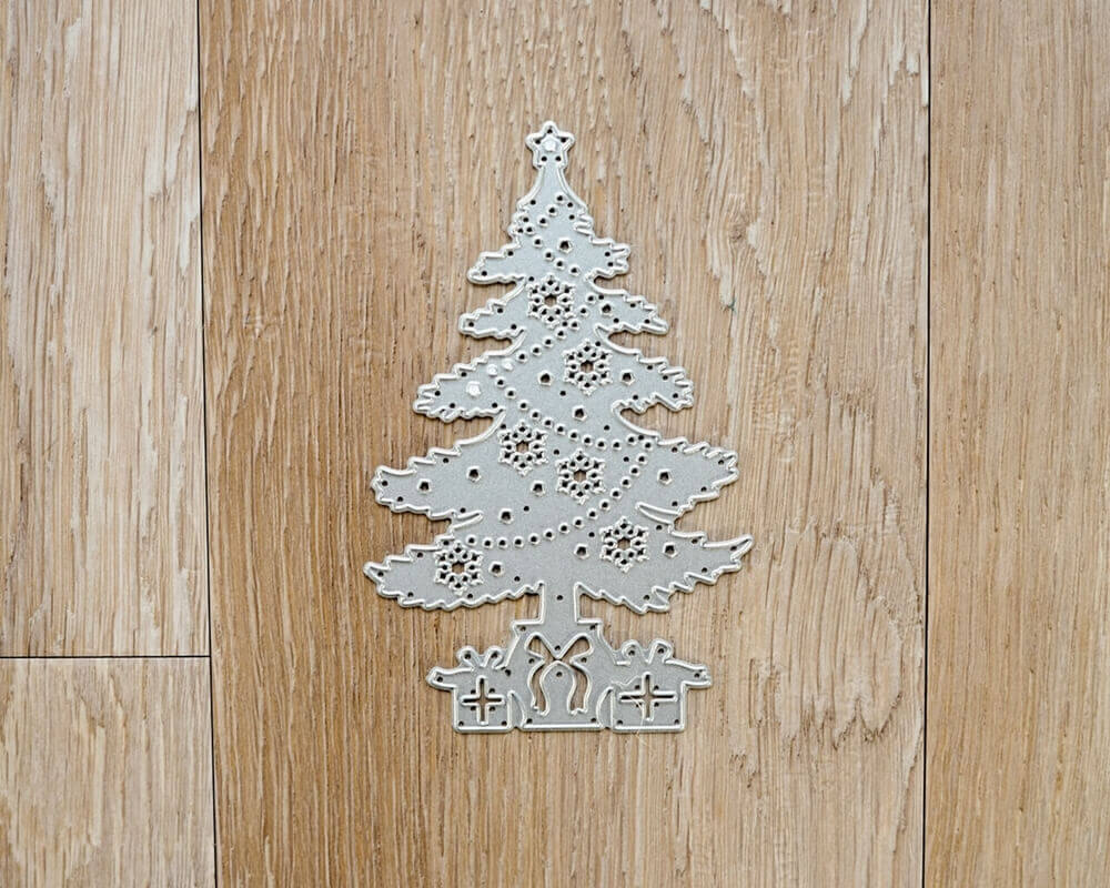 Eine silberne Stanzschablone: Weihnachtsbaum mit Geschenken auf Holzboden von Stanzenshop.de.
