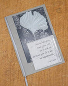 Eine Kondolenzkarte verziert mit der Stanzenshop.de Stanzschablone Zwei Ginkgoblätter und einem Goethe-Zitat auf der Vorderseite, platziert auf Holz - ideal zum Basteln oder für Scrapbooking-Projekte.