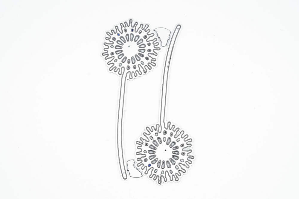 Die "Stanzschablone: Zwei Löwenzahn Pflanzen" von Stanzenshop.de ist eine Metallstanze in Form von zwei Löwenzähnen mit Stängeln, ideal für Scrapbooking oder Basteln. Abgebildet auf einem schlichten weißen Hintergrund.