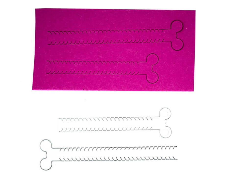 Eine Stanzschablone mit zwei Reißverschlüssen, eine Schere, die ein Stück Papier auf einem rosa Hintergrund schneidet.