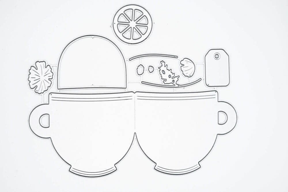 Umrisszeichnung von zwei Tassen nebeneinander mit Teezubehör oben, wie Zitronenscheibe und Anhänger-ideal als Stanzschablone Zwei Tassen mit Zubehör von Stanzenshop.de für Basteln und kreative Projekte.