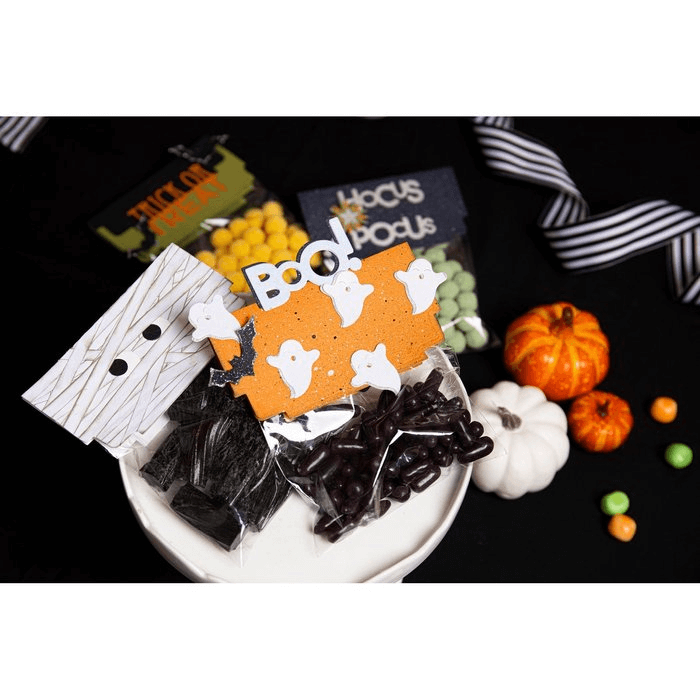 Eine Sizzix-Halloween-Leckerli-Tüte mit Süßigkeiten und Kürbissen auf einem Tisch.