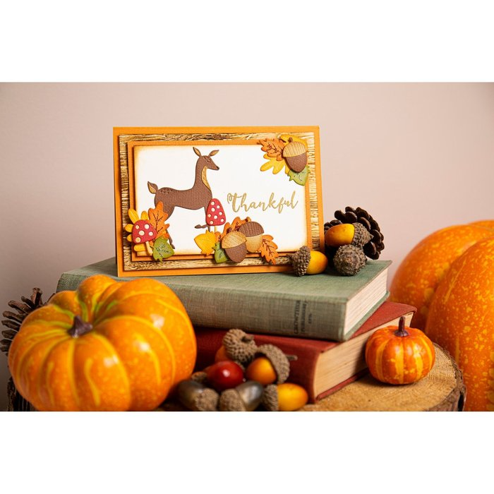 Eine Sizzix Thinlits Die Set Harvest Squirrels-Karte mit einem Hirsch und Kürbissen auf einem Stapel Bücher.